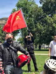 Antifa - Anti Trump leftist group - holding Hammer and Cycle communist flag while protesting Trump -